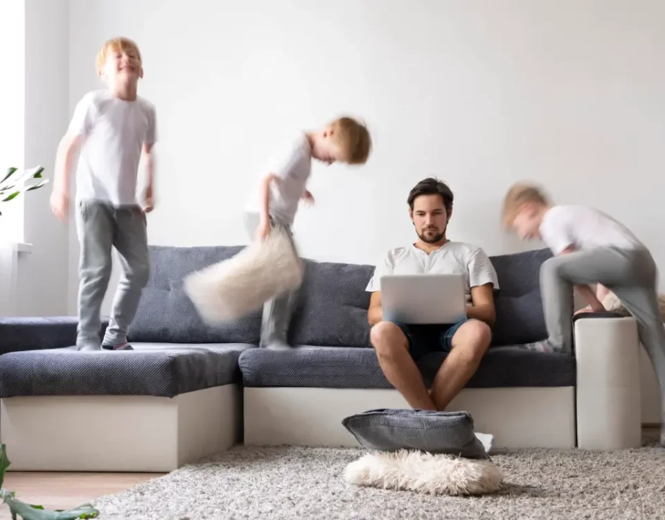 Padre trabajando mientras juega con hijos