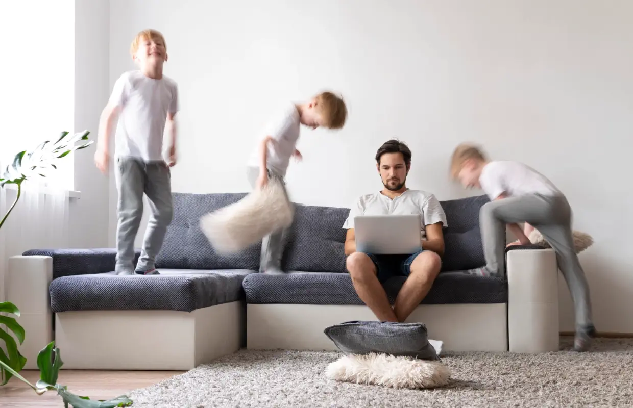 Padre trabajando mientras juega con hijos